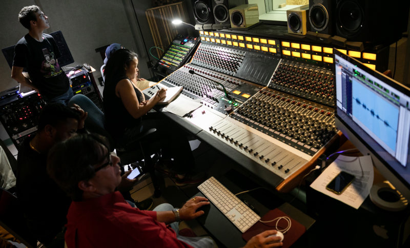 The instructor and students gathered around a sound board