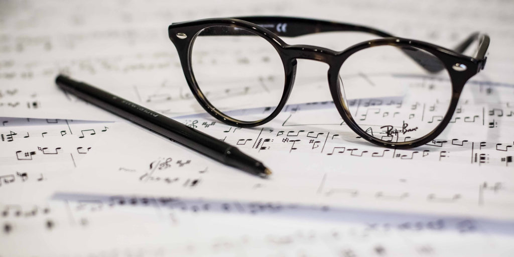 Sheet music with a pen and glasses on top